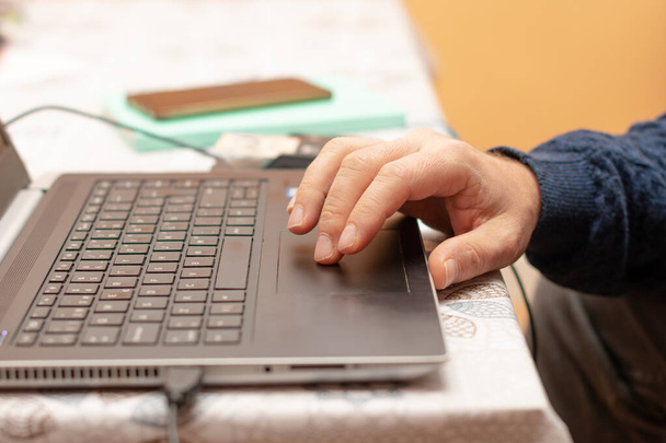 το χέρι ενός μεσήλικα που χρησιμοποιεί το φορητό υπολογιστή για να δουλέψει από το σπίτι το πρωί - Φωτογραφία, εικόνα