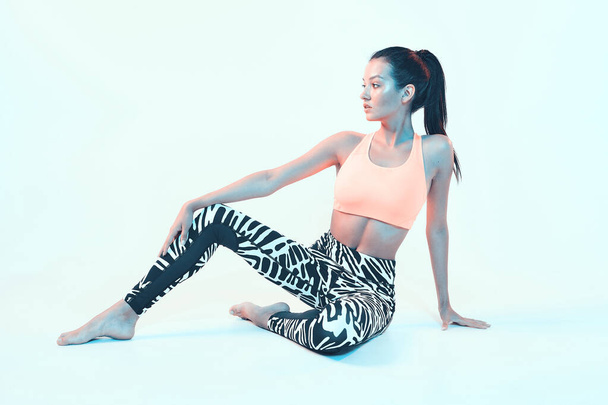 Fit young girl in stylish sportswear posing in neon studio light. Leggings for effective exercising, female wellness - Foto, Imagem
