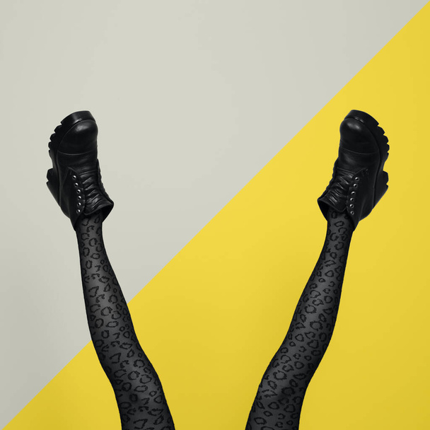Nowe szare damskie buty na długich smukłych kobiecych nogach w szarych rajstopach odizolowane na żółtym i szarym tle. Pop koncepcja sztuki z Heavy Duty Boots. - Zdjęcie, obraz