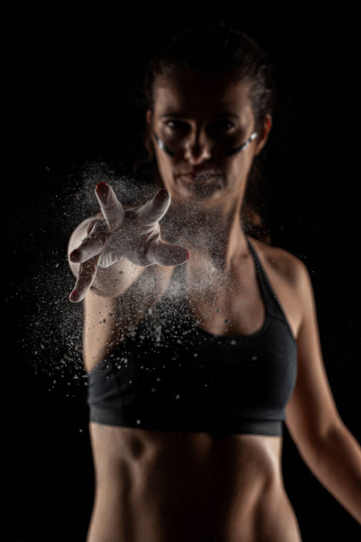 Kickboxer kirl with magnesium powder on her hands, punching with dust visible. - Foto, Imagem