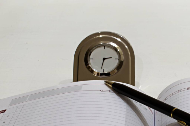 metal desk clock with diary and ballpoint pen on white background - Photo, Image