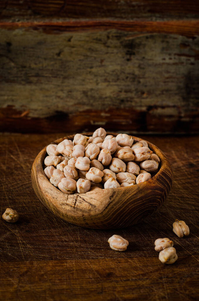Raw Chickpeas in a bowl on wooden backgraund. Chickpeas is nutritious food. Healthy and vegetarian food. Uncooked dried peas. Toned image - Foto, imagen