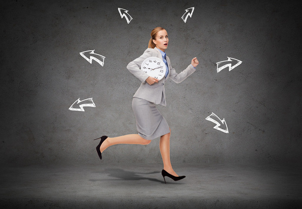 Stressed young businesswoman with clock running - Photo, Image