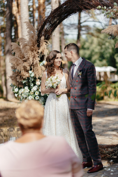Наречений і наречена в білій сукні на тлі арки. Весільна церемонія. Щаслива сім'я
. - Фото, зображення