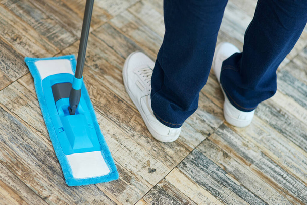 Temiz olmasına izin ver. Profesyonel erkek temizlikçi, mutfakta yerleri temizlerken paspas kullanıyor. - Fotoğraf, Görsel
