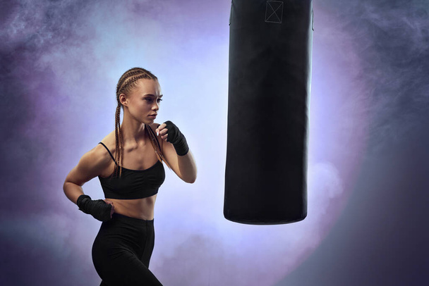woman with boxing bandages hitting the boxing bag - Фото, изображение
