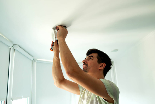 House master male electrician repairs ceiling light indoor home in white room - Foto, immagini