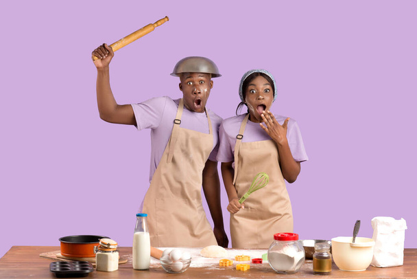 Couple afro-américain se sentant choqué tout en cuisinant ensemble sur fond de studio lilas - Photo, image