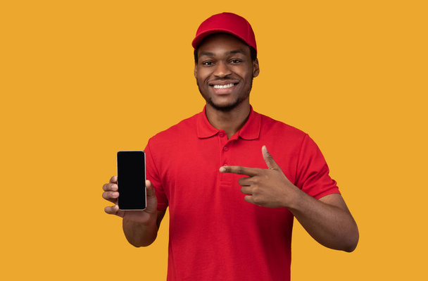 Schwarzer Zusteller hält Smartphone mit leerem Bildschirm für Attrappe - Foto, Bild