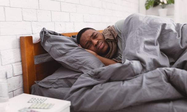 Unhappy Sick Black Guy Lying Wrapped In Blanket In Bedroom - Foto, imagen