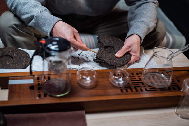 Közelről. A kínai teaszertartás mesterének kezei egy bambusz tűt tartanak a tea szedéséhez.. - Fotó, kép