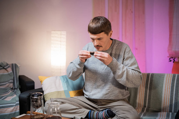 Молодий чоловік п'є смачний, ароматний чорний китайський чай зі скляної миски під час справжньої чайної церемонії вдома
. - Фото, зображення