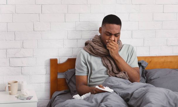 Chorym czarny człowiek kaszel Cierpiące zapalenie płuc siedzi w łóżku w pomieszczeniach - Zdjęcie, obraz