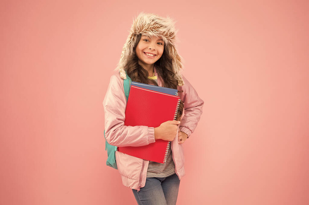 Expect the Best. back to school. winter holiday and vacation. kid warm clothes pink background. pupil daily life.schoolgirl carry backpack and books go home. no more exams. happy girl earflap hat - Photo, image