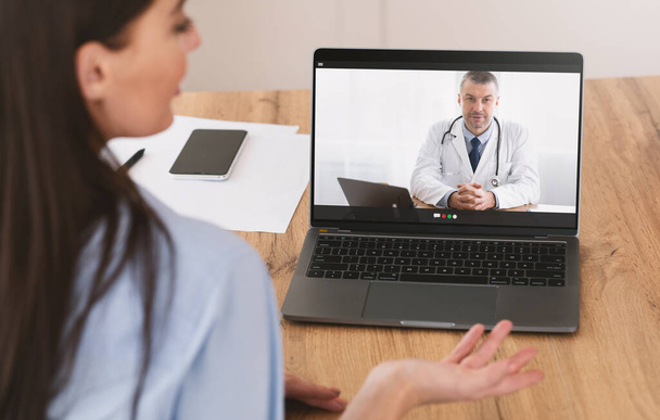 Cybermedicine. Female patient chatting with doctor online using laptop, having video call with health practitioner - Photo, image