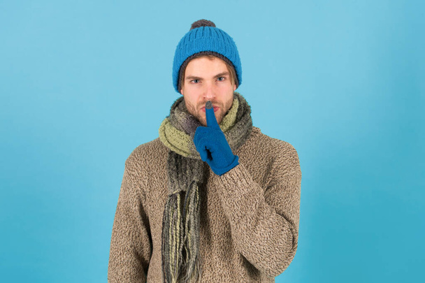 Keep my secret. Man handsome unshaven guy wear winter accessories on blue background. Winter season sale. Hipster knitted winter hat scarf and gloves. Emotional expression. Mysterious deal. Wish list - Foto, imagen