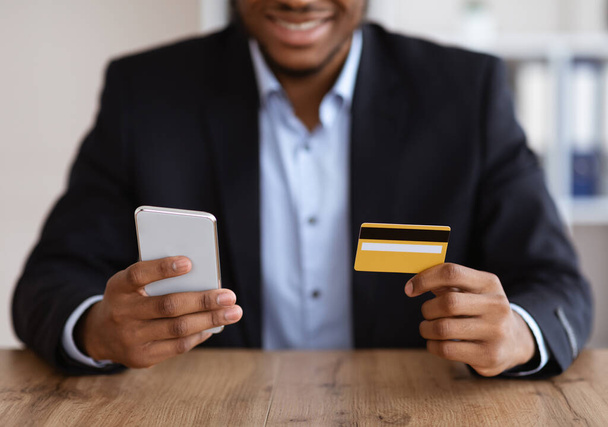 Hombre negro en traje con teléfono móvil y tarjeta de crédito - Foto, imagen
