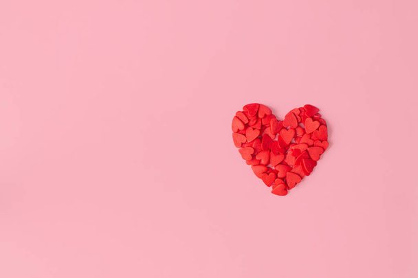 Heart lined with small red hearts on pink background. Flat lay. Copy space. - Fotó, kép