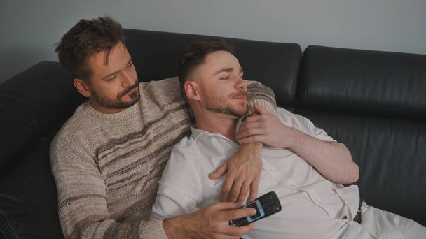 Young romantic gay couple spending day cuddling and relaxing on the couch. Different family lifestyle concept - 写真・画像