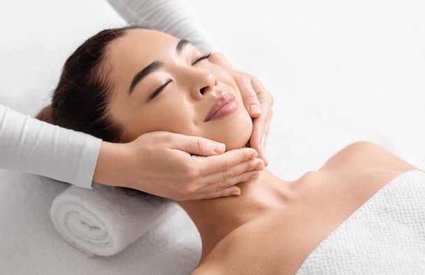 Massagem facial. Closeup de atraente mulher asiática recebendo tratamento de beleza no spa - Foto, Imagem
