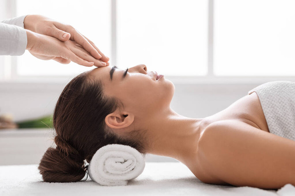 Beautiful asian woman in spa salon enjoying acupressure head massage, side view - Foto, imagen