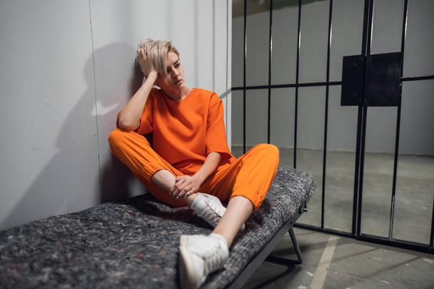 Hapisteki ranzasında turuncu tulumlu uyuşturucu satıcısı olarak hüküm giymiş bir kız. - Fotoğraf, Görsel