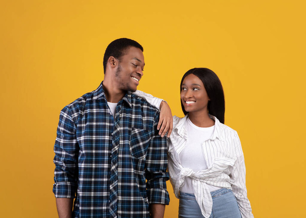 Ρομαντικά και προσωπικά συναισθήματα. Νεαρός ευτυχισμένος Αφροαμερικάνος άντρας και κυρία σε casual κοιτάζονται στα μάτια - Φωτογραφία, εικόνα