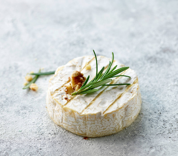 świeży ser brie z rozmarynem i orzechem włoskim na jasnomalowanym tle - Zdjęcie, obraz