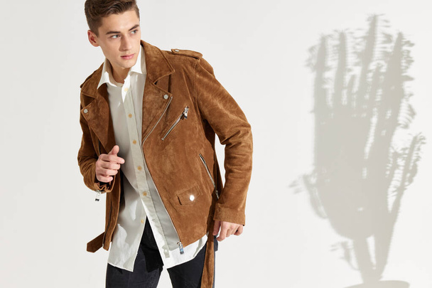 um cavalheiro de camisa e uma jaqueta em um fundo leve gestos com as mãos - Foto, Imagem