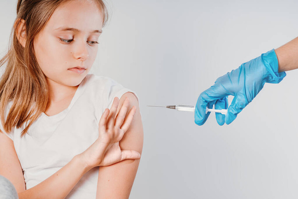 Impfung: Anti-Impfung gegen Coronaviren: Mädchen zeigt Arzt die Hand und verweigert Impfung gegen Coronaviren - Foto, Bild