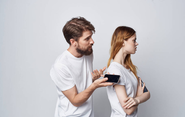 man and woman in white t-shirts with phones in hands romance communication technology - Fotoğraf, Görsel
