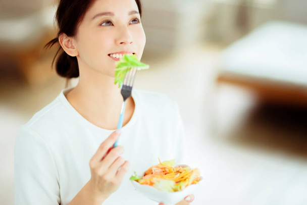 Giovane donna felice mangiare insalata sana a casa - Foto, immagini