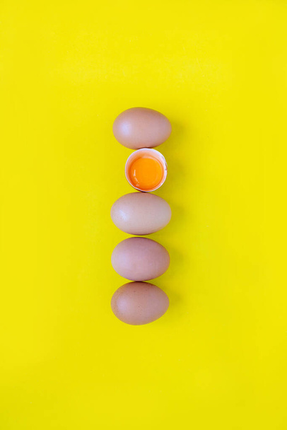 Closeup cracked brown eggs Buy from supermarket Placed side by side on a yellow background - 写真・画像
