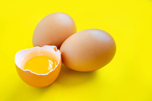 Nahaufnahme geknackte braune Eier aus dem Supermarkt auf gelbem Hintergrund. - Foto, Bild