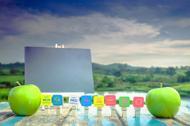 Clothespin clipped cards and green apple on wooden table in the sunlight with  a blurred nature  background. - Foto, Imagem