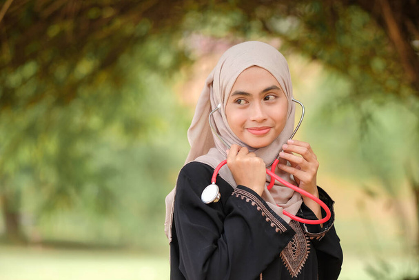 Молода недосвідчена жінка-лікар з хіджабом, що тримає стетоскоп у лікарняному саду. Медична та медична служба концепція. - Фото, зображення