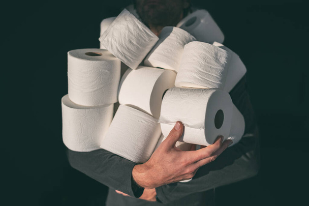Toilet paper shortage coronavirus panic buying man hoarding carrying many rolls at home in fear of corona virus outbreak closing shopping stores - Foto, imagen