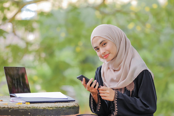 Retrato de mulher muito muçulmana vestindo hijab usando smartphone.Technology e conceito de comunicação. - Foto, Imagem