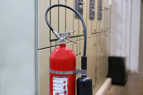 El extintor rojo está listo para su uso en caso de una emergencia de incendio en interiores. - Foto, imagen