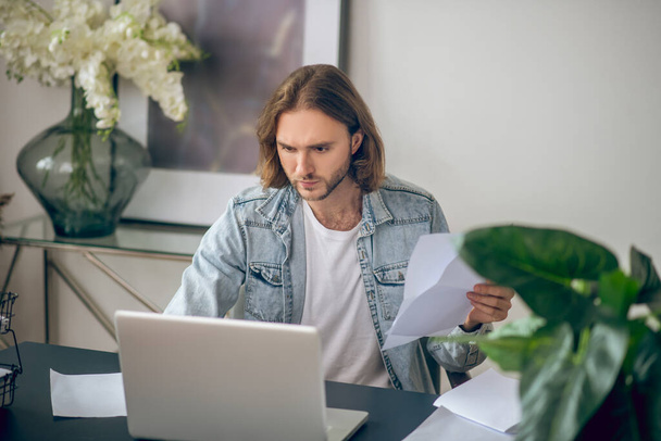 Young man in jeans shirt working on a laptop - Photo, Image