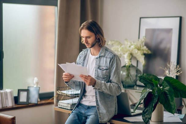 Young man in jeans shirt holding papers - Photo, Image