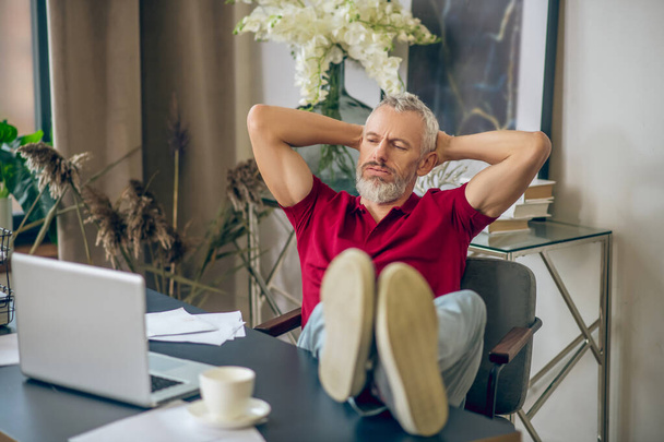 Grey-haired man sitting at the laptop and looking bored - Foto, Imagen