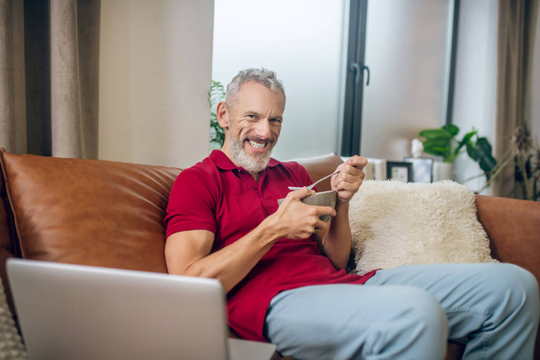 Grey-haired man having lunch and watching a video - Φωτογραφία, εικόνα