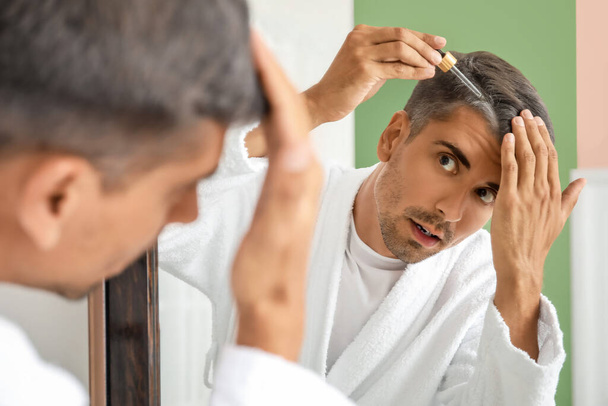 Homme aux cheveux gris utilisant du sérum à la maison - Photo, image