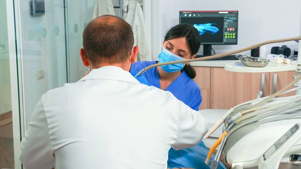歯科医とアシスタントは、現代の歯科クリニックで患者と仕事をします - 写真・画像
