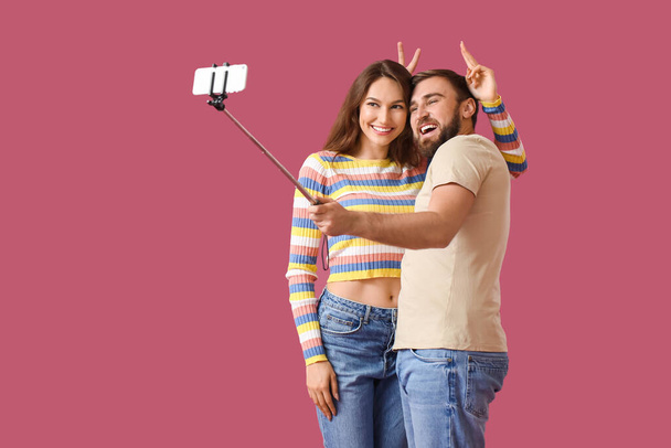Pareja joven tomando selfie sobre fondo de color - Foto, Imagen