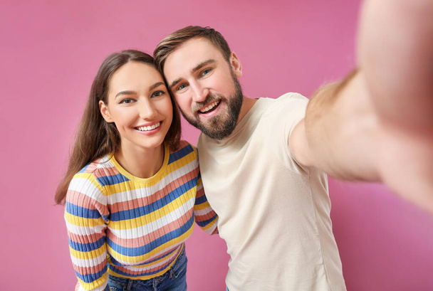 Jeune couple prenant selfie sur fond de couleur - Photo, image