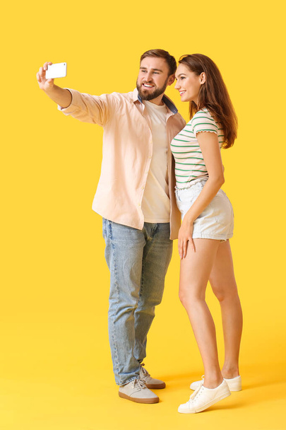Young couple taking selfie on color background - Photo, image