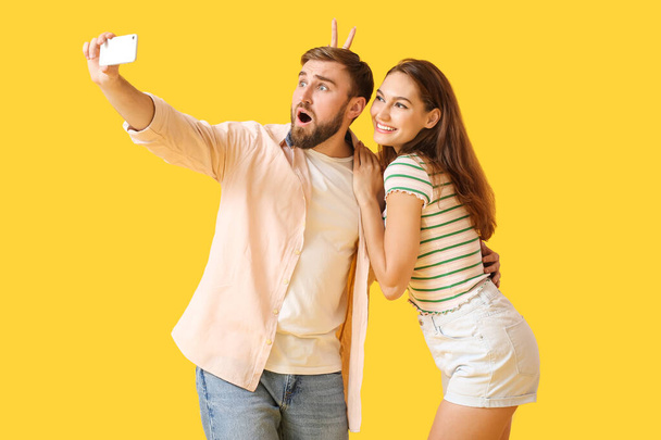 Pareja joven tomando selfie sobre fondo de color - Foto, imagen