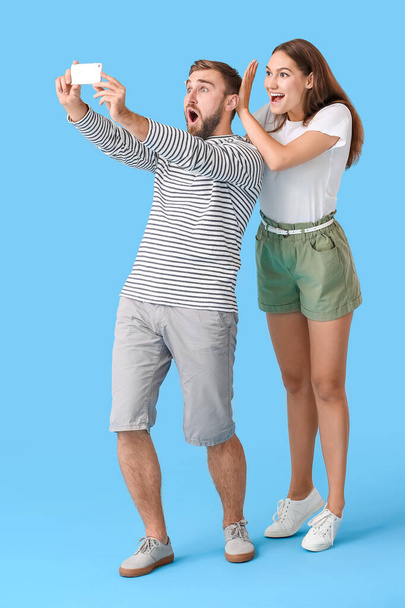 Νεαρό ζευγάρι που παίρνει selfie στο φόντο χρώμα - Φωτογραφία, εικόνα